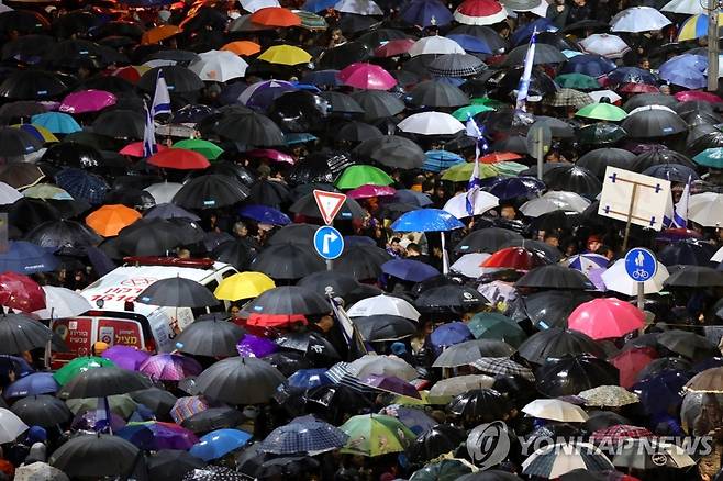 비 내리는 가운데 열린 이스라엘 '사법개혁안' 반대시위 (텔아비브 EPA=연합뉴스) 14일(현지시간) 이스라엘 텔아비브에서 우산을 쓴 시민들이 새 정부의 '사법개혁안'에 반대하는 시위를 벌이고 있다. (EPA/ABIR SULTAN) 2023.1.15. photo@yna.co.kr