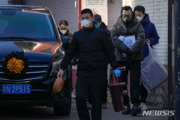 19일 중국 베이징의 한 발열 전담병원에서 사람들이 영정사진과 장례용품 등을 들고 운구차량 옆을 지나고 있다. [사진=뉴시스]