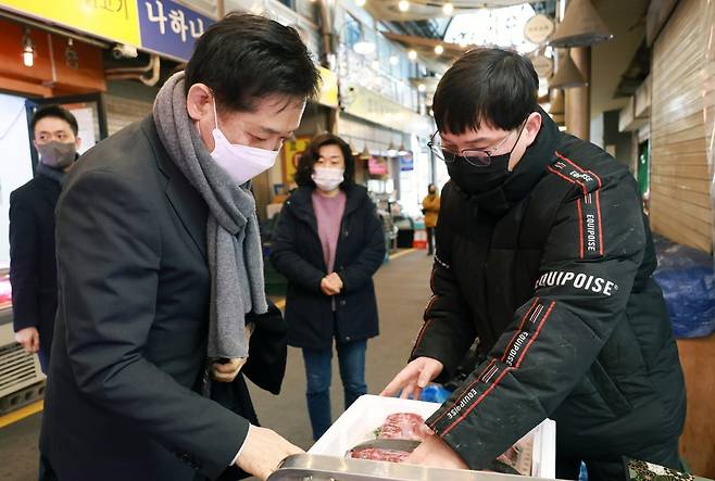 김주현 금융위원장(왼쪽)이 16일 오전 구정 설 명절을 앞두고 서울 종로구 소재 통인시장을 방문해 과일, 고기 등 명절 성수품을 직접 구입하면서 전통시장 내 소상공인의 애로사항을 듣고 있다./사진=금융위원회