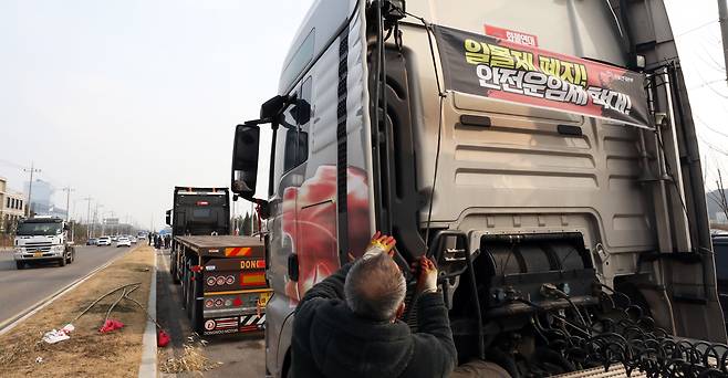 충남 당진시 현대글로비스 앞에서 파업 농성을 하던 화물연대 조합원이 화물차량에 부착한 '일몰제 폐지!, 안전운임제 확대' 플래카드를 철거하고 있다. /뉴스1