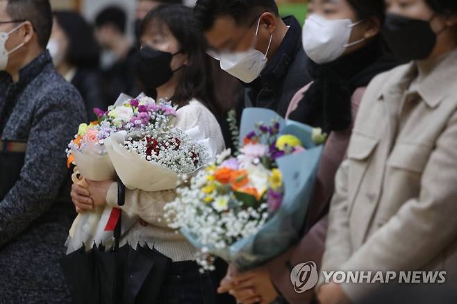 가족과 함께하는 졸업식 '3년 만' (광주=연합뉴스) 차지욱 기자 = 코로나19 확산 이후 3년 만에 가족들이 참석한 졸업식이 열린 13일 오전 광주 서구 서초등학교에서 학부모들이 꽃다발을 들고 있다. 2023.1.13 uk@yna.co.kr