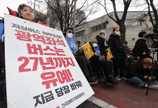 전국장애인차별철폐연대(전장연) 회원이 19일 오후 서울 서초구 남부터미널 앞에서 열린 시외버스 이동권 촉구 집회에서 팻말을 들고 있다. 연합뉴스