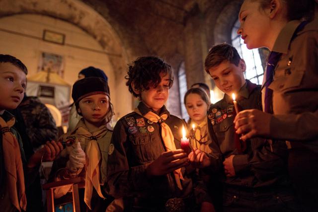 지난해 12월 25일 우크라이나 하르키우에서 보이스카웃 대원들이 성탄절 예배 도중 촛불을 들고 있다. 하르키우=AP 연합뉴스
