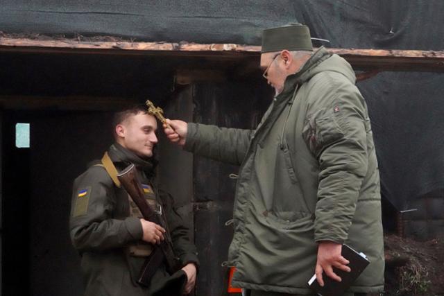 지난해 12월 24일 우크라이나 하르키우 인근 방위군 진지에서 한 군목이 성탄절을 기념하며 한 병사를 축도하고 있다. 하르키우=AP 연합뉴스