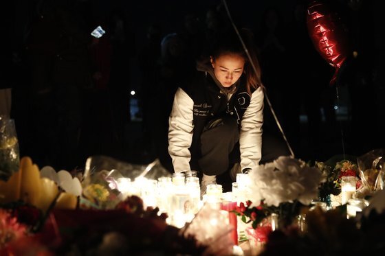 미국 캘리포니아주 몬터레이 파크 시청 앞에서 한 시민이 총격 사건 추모자를 위한 추모비에 촛불을 켜고 있다. EPA=연합뉴스