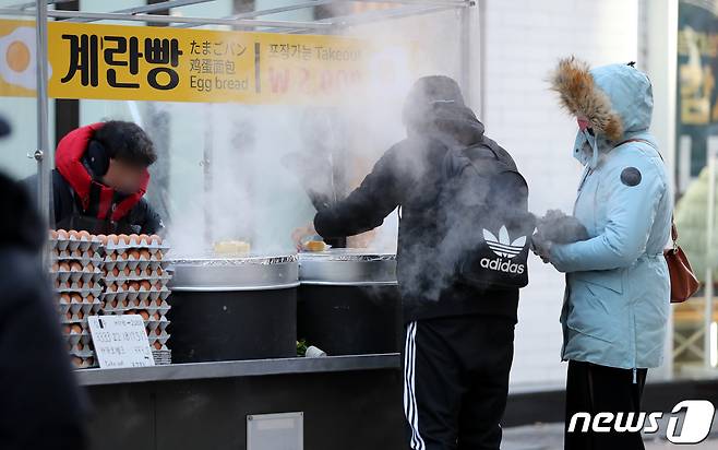 전국에 한파 특보가 내려진 24일 오후 서울 중구 명동거리를 찾은 시민들이 계란빵을 구입하고 있다. 2023.1.24/뉴스1 ⓒ News1 김진환 기자