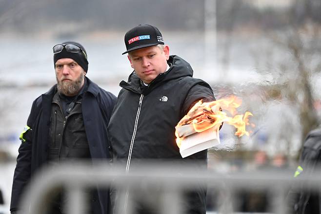 덴마크 극우정당 ‘스트람 쿠르스’의 지도자 라스무스 팔루단이 지난 21일(현지시간) 스웨덴 스톡홀름 튀르키예 대사관 앞 시위에서 이슬람 경전인 쿠란을 불태우고 있다. 로이터연합뉴스