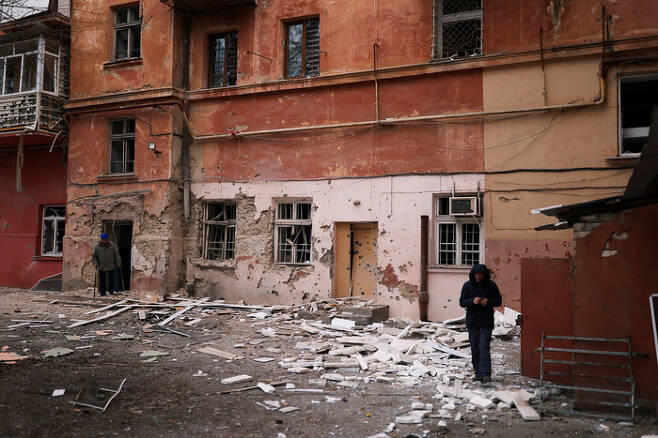 25일(현지시간) 우크라이나 헤르손에서 한 주민이 러시아군의 포격으로 파손된 건물 앞을 지나고 있다. 로이터연합뉴스