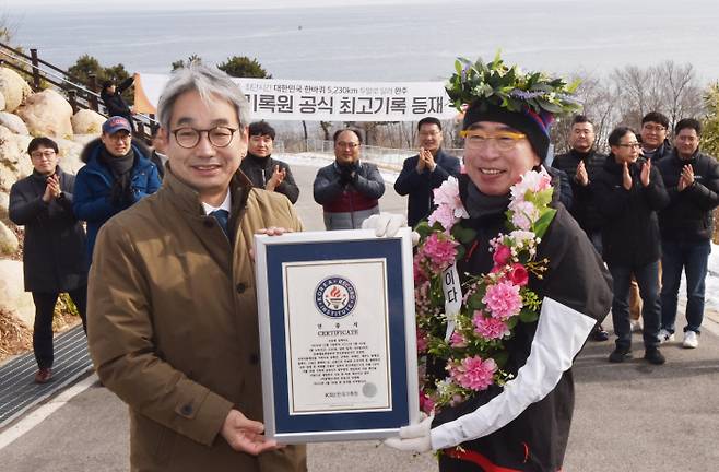 조웅래씨(오른쪽)가 26일 강원 고성군 통일전망대 앞에서 ‘대한민국 국토 경계 한 바퀴 최단시간 완주 기록’ 인증서를 받고 기념촬영을 하고 있다. 맥키스컴퍼니 제공