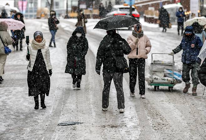 서울을 포함한 수도권에 눈이 내린 26일 오전 서울 중구 명동에서 시민들이 눈을 맞으며 이동하고 있다. 뉴시스