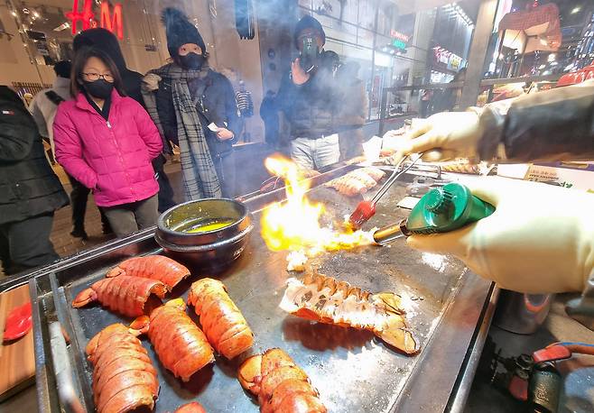 20일 오후 서울 명동을 찾은 외국인 관광객들이 랍스터 노점 앞에 서 있는 모습. /남강호 기자