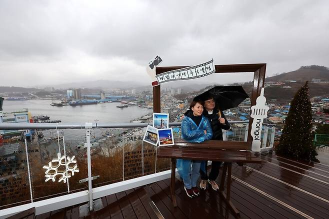 강원도 동해시 논골담길 ‘바람의 언덕’ 정상에 오른 안희택(오른쪽)·최희영 부부가 액자 틀 안에 들어가 바다를 배경으로 추억을 남기고 있다.