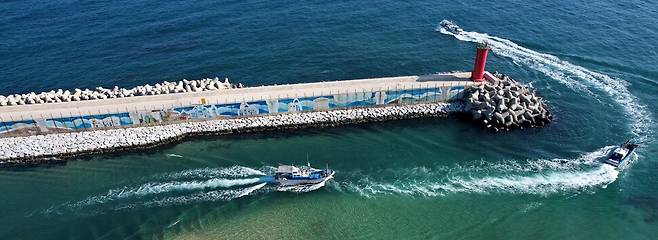 방파제를 따라 벽화가 그려진 강릉시 연곡면 영진항에서 어선들이 등대를 돌아 출항하고 있다.