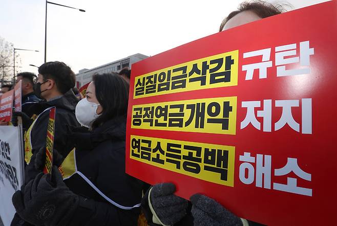 한국노총 공무원노동조합연맹·교사노동조합연맹·전국우정노조로 구성된 공무원연금개악저지 공동투쟁본부 조합원들이 지난달 6일 오전 서울 용산구 전쟁기념관 앞에서 열린 ‘연금개악저지 전국 릴레이 투쟁 서울지역 기자회견’에서 실질임금삭감과 연금통합시도 등을 규탄하며 손팻말을 들고 있다. [출처 : 연합뉴스]