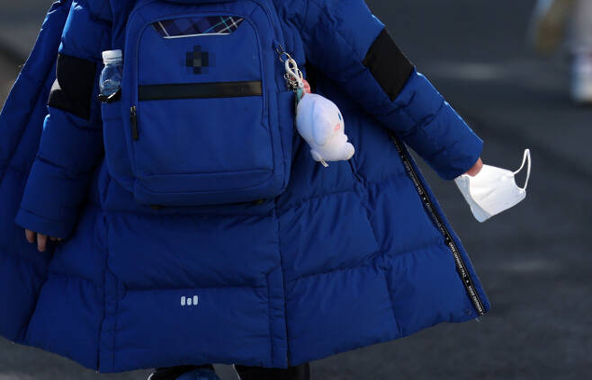 25일 오후 부산 남구 한 초등학교에서 한 학생이 마스크를 손에 쥐고 하교하고 있다. 연합뉴스
