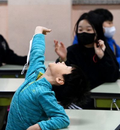 30일 서울 광진구 광장초등학교 교실에서 한 학생이 마스크 벗을 사람을 묻는 교사의 질문에 손을 들어 답하고 있다. 사진공동취재단
