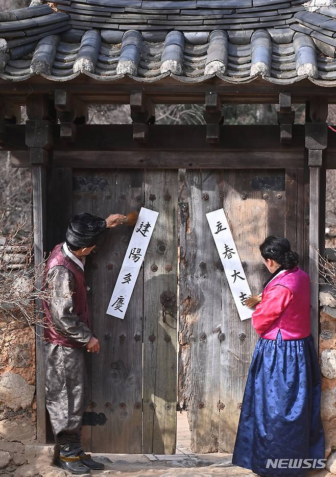 [용인=뉴시스] 김종택 기자 = 절기상 입춘을 이틀 앞둔 2일 오전 경기도 용인 한국민속촌에서 관계자들이 '입춘대길(立春大吉)', '건양다경(建陽多慶)' 등 입춘첩을 붙이고 있다. 2023.02.02. jtk@newsis.com