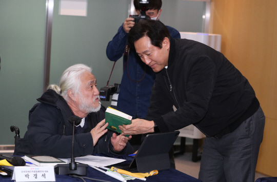지난 2일 서울시청에서 오세훈(오른쪽) 시장이 전국장애인차별철폐연대(전장연)와 간담회를 하는 도중 박경석(왼쪽) 전장연 상임공동대표에게 자료를 받고 있다. 공동취재사진