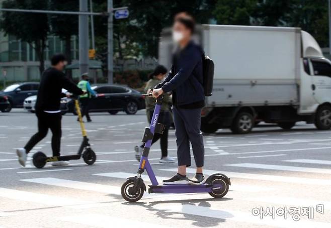 서울 시내에서 시민들이 전동퀵보드 타고 이동하고 있다. ‘제2종 원동기장치자전거면허’ 이상의 운전면허증 보유자만 전동 킥보드를 탈 수 있고 헬멧 없이 탑승하면 2만 원의 범칙금이 부과된다. 사진은 기사 내용과 무관.