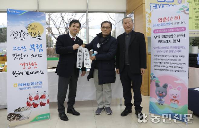 조근수 NH농협은행 경남본부장(왼쪽)이 이성곤 서예가(오른쪽)와 함께 농협을 방문한 고객을 대상으로 입춘첩 써드리기 행사를 하고 있다.