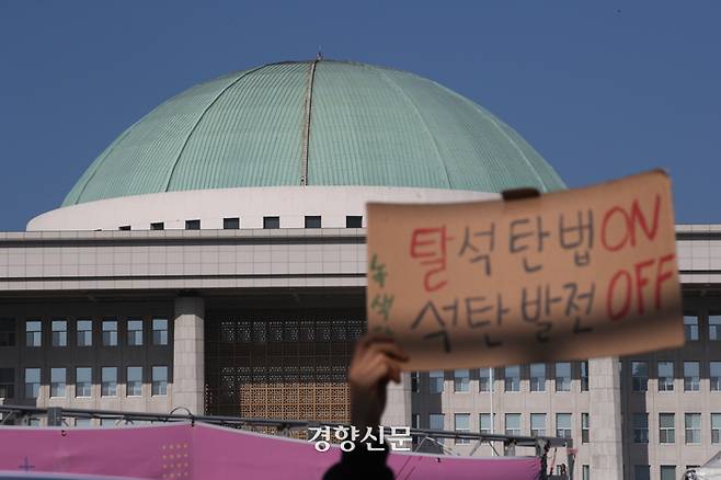 탈석탄법 제정을 위한 시민사회연대가 지난해 11월 23일 서울 국회 앞에서 열린 기자회견에서 삼척 석탄발전 최초 점화 중단과 탈석탄법 제정을 촉구하는 손팻말을 들고 있다. 성동훈 기자