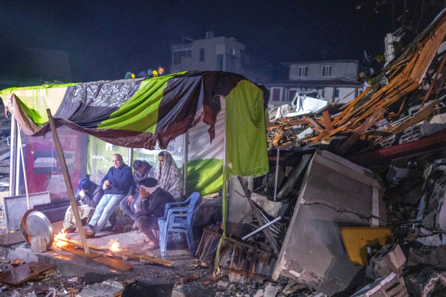 84년 만에 튀르키예(터키)를 강타한 대형 지진에 집을 잃은 하타이 지역 이재민들이 6일 간이 대피소에서 영하의 추위를 견디기 위해 모닥불로 몸을 녹이고 있다.   AFP 연합뉴스