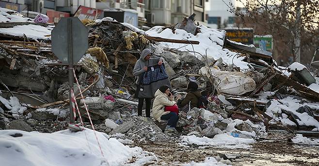 7일(현지시간) 튀르키예 말라티아 주민들이 지진으로 무너진 건물 잔해 주변에 모여 앉아 있다. 지진 피해 주민들은 영하의 기온에도 불구하고 여진으로 인한 추가 붕괴 위험으로 거리에서 밤을 지새우는 것으로 알려졌다. 말라티아=AP뉴시스