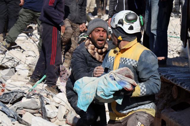 8일(현지시간) 시리아 이들리브주(州) 하림의 한 남성이 건물 잔해 속에서 사망한 자신의 아이를 끌어내 다른 곳으로 데려가는 구조대원의 팔을 붙들고 있다. 하림=AFP 연합뉴스