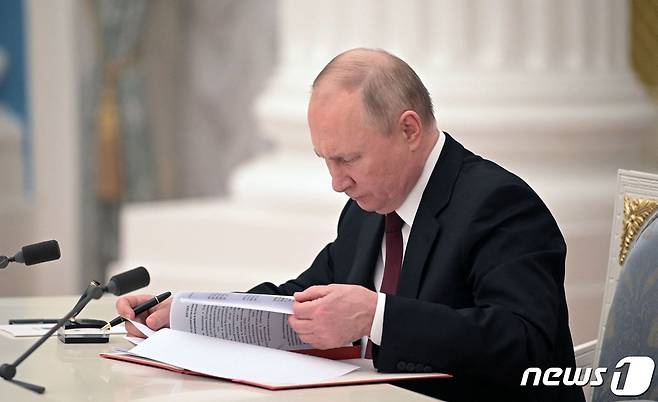 블라디미르 푸틴 러시아 대통령이 21일(현지시간) 모스크바 크렘린에서 우크라이나 동부 지역에 있는 도네츠크인민공화국과 루간스크인민공화국의 독립을 승인하고 평화유지군 파견을 지시하는 대통령령에 서명을 하고 있다. ⓒ AFP=뉴스1 ⓒ News1 우동명 기자