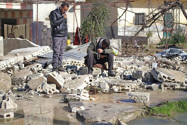 9일(현지 시각) 시리아 반군이 장악하고 있는 이들리브 살킨(Salqin) 알툴루 마을에서 지역 남성 2명이 파괴된 건물 옆에 모여 좌절하고 있다./AFP 연합뉴스