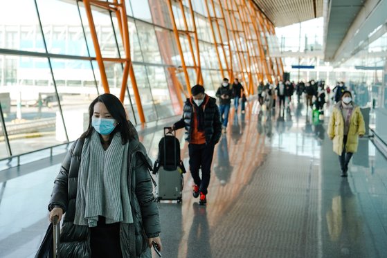 지난 28일 중국 베이징 서우두 공항에 마스크를 쓴 승객들이 수하물을 들고 입국하고 있다. EPA=연합뉴스