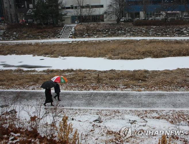 눈 내리기 시작한 대전 (대전=연합뉴스) 이주형 기자 = 26일 오후 대전지역에 눈이 내리기 시작한 가운데, 시민들이 우산을 쓰고 유성구 봉명동 유성천 산책로를 걷고 있다. 2023.1.26 coolee@yna.co.kr