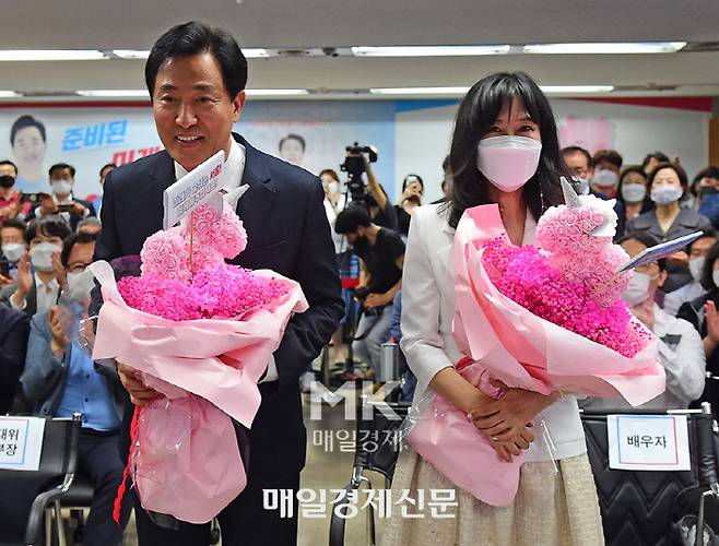 오세훈 시장이 지난 6월 2일 캠프 개표상황실에서 당선이 확실시되자 부인 송현옥 씨와 꽃다발을 받고 기뻐하는 모습. 뉴진스와 기념 촬영할 때보다는 웃음의 강도가 약해 보인다. [매경db]