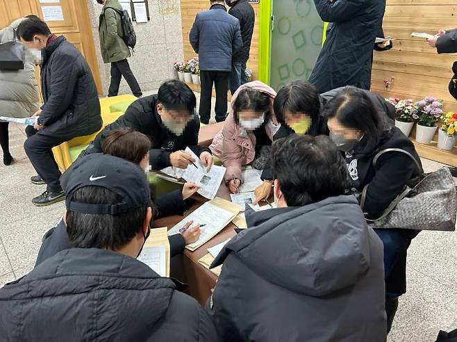 지난 14일 방문한 수원지방법원 안양지원 104호 매각법정 앞에서 현장학습을 나온 사람들이 기일입찰표를 작성하며 경매 공부에 열중하고 있는 모습.[사진=곽민재 기자]
