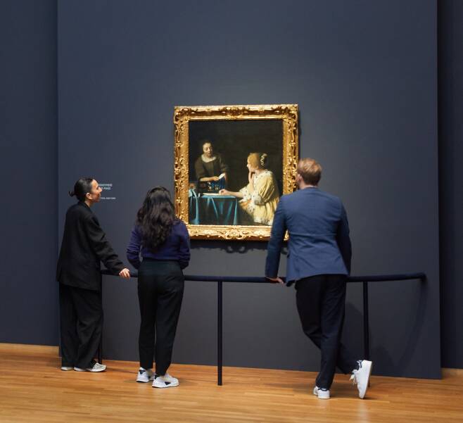 그림 보호용 펜스를 짚은 채 관람객들이 ‘여주인과 하녀’(1665~67)를 관람하고 있다. /Rijksmuseum