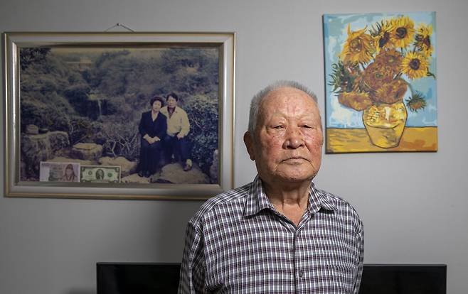 1956년 북한 황해도 고향에서 남한 북파공작원에게 납치된 지 67년 만에 국가의 배상을 받게 된 김주삼(86)씨가 2023년 2월20일 경기도 고양시 자택에서 포즈를 취했다. 벽에는 김씨와 부인 이승자씨 부부의 젊은 시절 사진과 딸이 그린 고흐의 해바라기 정물화가 나란히 걸려 있다.