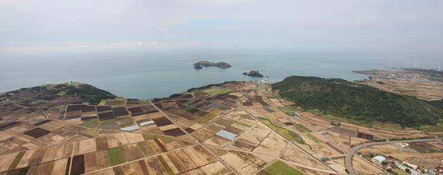 공중에서 촬영한 제주 고산리 유적 전경. 숲으로 덮인 오른쪽 수월봉과 기상관측탑이 세워진 왼쪽 당산봉 사이의 지점으로 평야지대다. 맞은편에 보이는 섬은 차귀도다.
