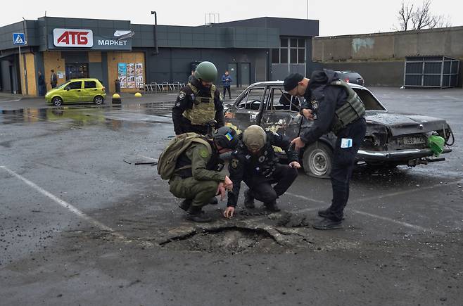 11일 우크라이나 남부 헤르손에서 경찰 수사관들이 슈퍼마켓 주차장에서 러시아군의 포탄 잔해를 조사하고 있다. /로이터·연합뉴스