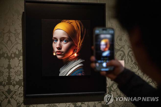 AI가 그린 '진주 귀걸이를 한 소녀'를 보는 관람객 (AFP=연합뉴스) 9일(현지시간) 네덜란드 헤이그의 마우리츠하위스 미술관에서 한 관람객이 AI가 그린 '진주 귀걸이를 한 소녀' 모작을 보고 있다. 재판매 및 DB금지.