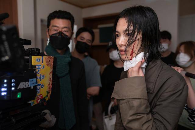 왼쪽 얼굴에 칼로 베인 분장을 한 배우 송혜교가 드라마 '더 글로리' 파트2를 촬영하며 카메라로 촬영분을 보고 있다. 넷플릭스 제공
