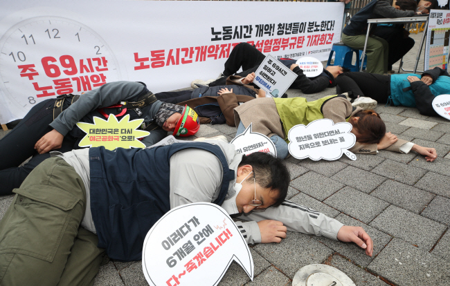 민주노총 조합원들이 지난 9일 서울 용산구 대통령집무실 앞에서 근로시간제도 개편방안을 반대하는 과로사 퍼포먼스를 벌이고 있다. 뉴시스