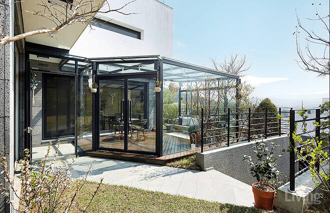 정원에서 보이는 선룸. 프레임을 최소화한 디자인이 특징으로, 2층의 수평 창과 조화를 이루며 차분하고 정돈된 분위기를 연출한다