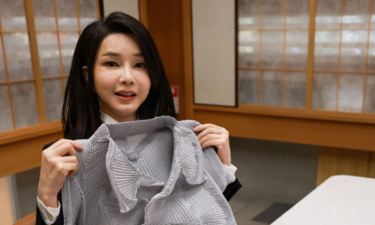 건축가 안도 다다오로부터 이세이 미야케의 옷을 선물받은 김건희 여사가 옷을 들어보이고 있다. 사진 뉴시스.