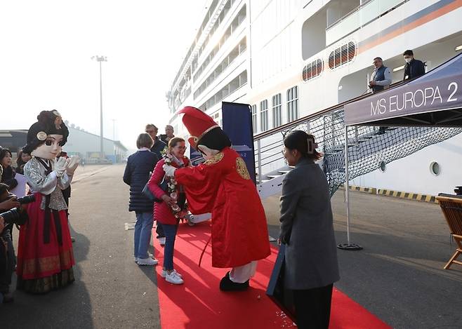 19일 인천항에 입항한 크루즈선 유로파2호의 첫 하선 승객에게 인천항만공사가 꽃다발을 목에 걸어주고 있다.|인천항만공사 제공