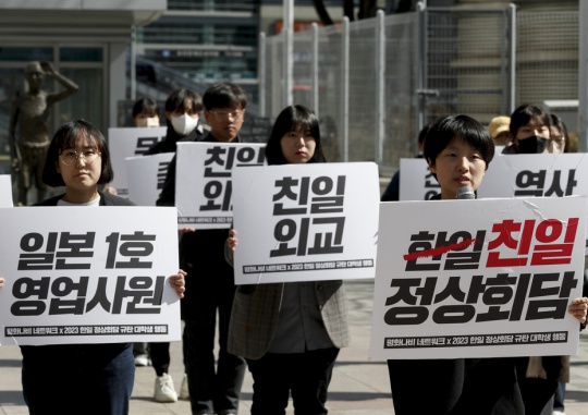Members of the Peace Nabi (butterfly) Network hold signs at a march by university students condemning the remorseless South Korea-Japan summit and refusing the shameful solution to forced mobilization in front of a statue portraying a worker seized and forced into labor at the square in front of Yongsan Station, Seoul on March 16. Mun Jae-won
