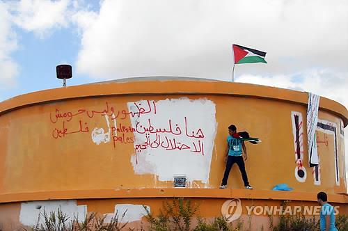 요르단강 서안 호메시의 폐쇄된 불법 정착촌에서 히브리어 표식을 지우는 팔레스타인 주민. [EPA 연합뉴스 자료사진. 재판매 및 DB 금지]