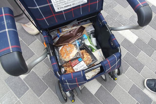 로손에서 구매한 식료품을 보여주고 있는 미즈사와 히로시씨. 식료품이 든 보행기는 물건을 담을 수도 있고, 뚜껑을 닫고 앉을 수도 있는 기능을 가지고 있다. 지바=이현주 기자