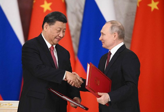 시진핑 중국 국가주석과 블라디미르 푸틴 러시아 대통령이 21일 모스크바에서 공동성명서를 나란히 들고 악수를 하고 있다. AFP=연합뉴스