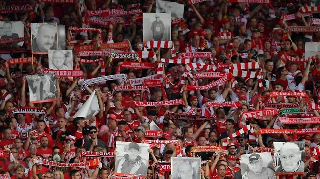 우니온 베를린 팬들이 분데스리가에서 맞이한 첫 경기에 팀의 승격을 미처 보지 못하고 하늘로 간 가족, 지인들의 사진을 들고 응원을 펼치고 있다. / 트위터