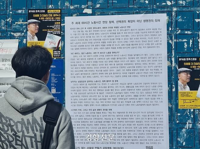 한 서울대 학생이 21일 서울대 관악캠퍼스 학생회관 앞에서 ‘비정규직 없는 서울대 만들기 공동행동(비서공)’의 주69시간 노동시간 개편안 철회 요구 대자보를 읽고 있다. 전지현 기자